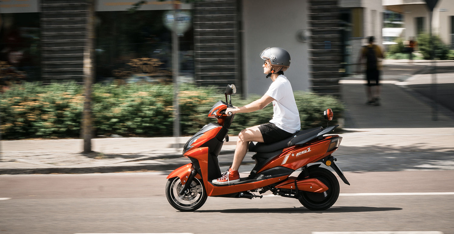 Kille som kör röd elmoped genom stan