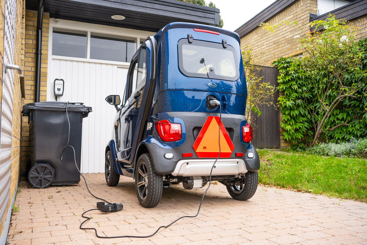 Elmopedbil som laddas vid hus genom laddbox