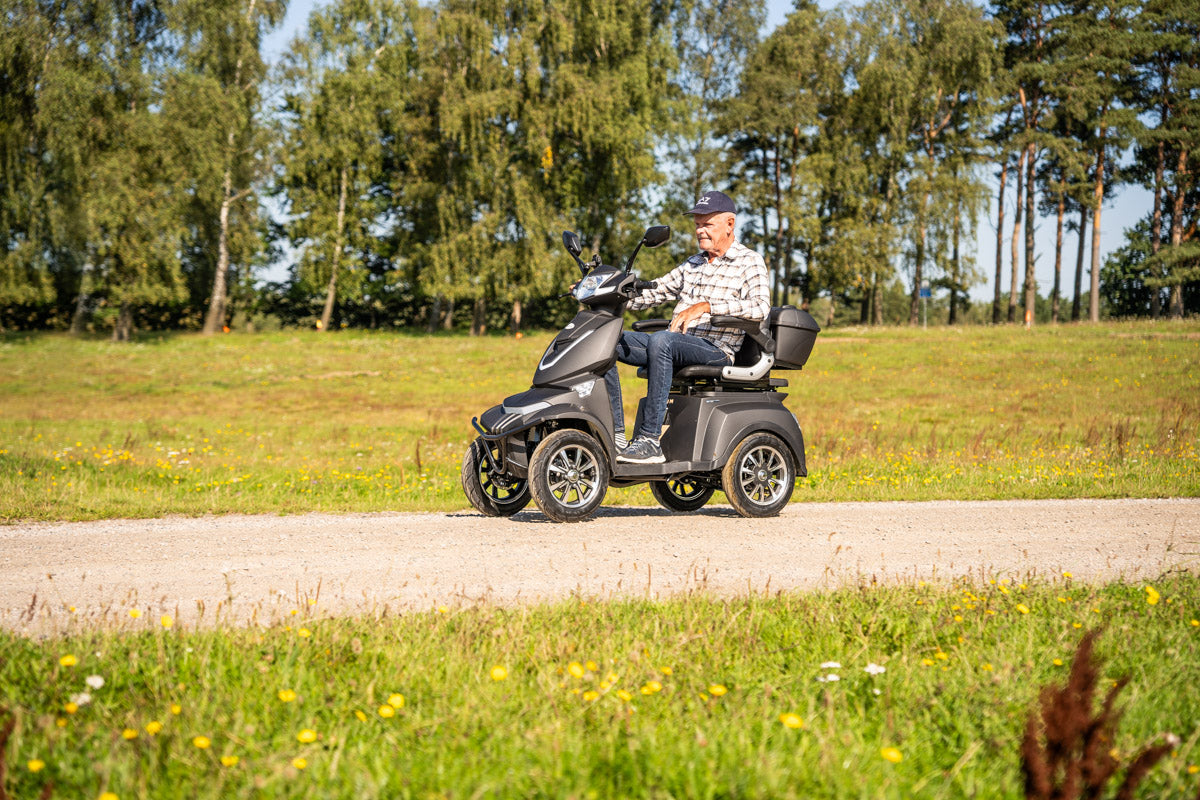 Äldre man kör promenadscooter Eloped Elite X på grusväg